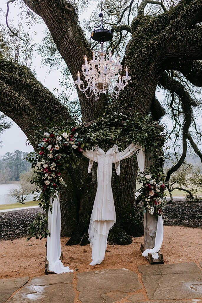 wedding gown hanging from ceremony arbor