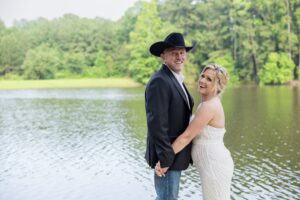 Houston Texas wedding venue bride and groom pose for wedding day photos by a waterfront wedding ceremony, outdoor ceremony with forest backdrop