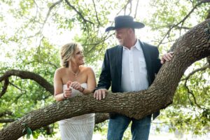 Houston Texas wedding venue bride and groom pose for wedding day photos by a waterfront wedding ceremony, outdoor ceremony with forest backdrop