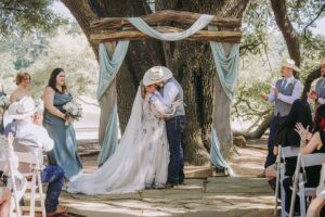 Top 100 Houston Sites for Engagement Photos 9 Bride and groom kissing at lakefront wedding ceremony near Houston