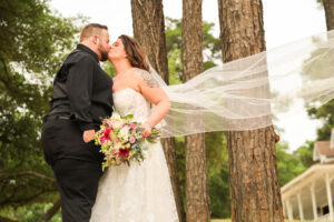 Bride in lace wedding gown and veil standing beneath the illuminated oak tree at Pine Lake Ranch near Houston.