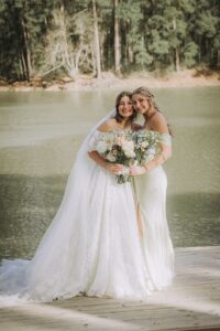 Bride and bridesmaid pose for wedding day photos at a lakeside wedding venue near Houston
