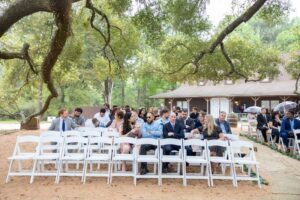 Planning The Perfect Houston Wedding Weekend 8 Wedding guests seated an a lakefront wedding venue waiting for the bride and groom at a garden wedding venue near Houston